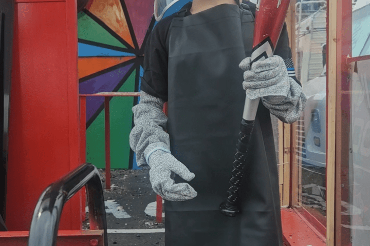 Person in protective gear holding a red baseball bat indoors.