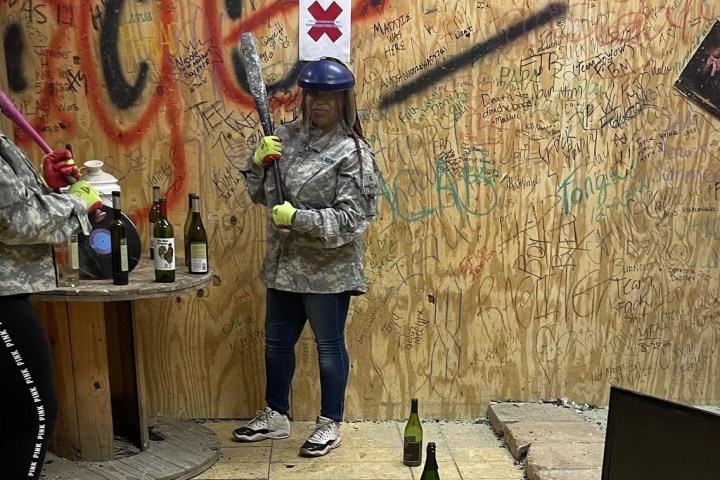 Two people in helmets holding bats in a graffiti-covered room.