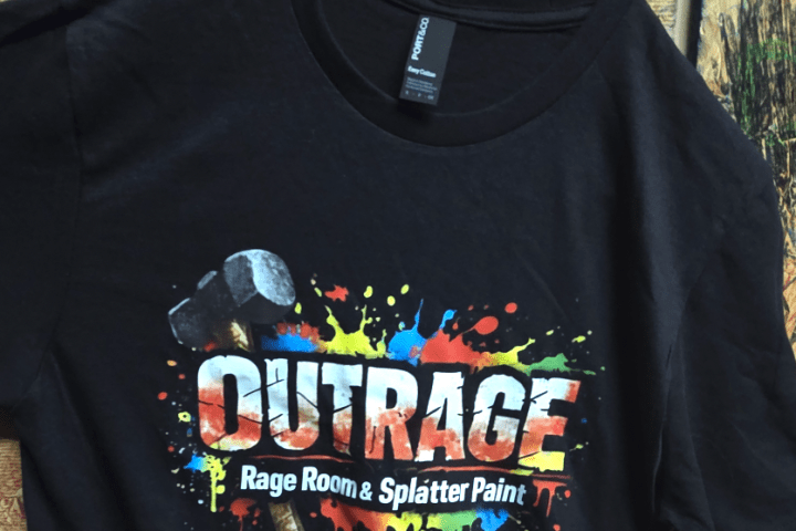 Black t-shirt with colorful splatter design and sledgehammer, text: OUTRAGE Rage Room & Splatter Paint.