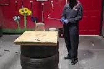 Person in protective gear standing in room with graffiti, next to a wooden platform on tires.